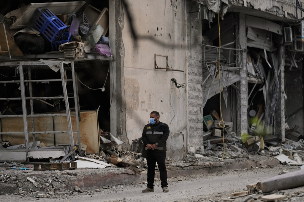 A member of Hezbollah stands guard next to a destroyed building in Dahiyeh, Beirut's southern suburbs, Lebanon, Friday, April 17, 2026, following a ceasefire between Israel and Hezbollah. (AP Photo/Bilal Hussein)