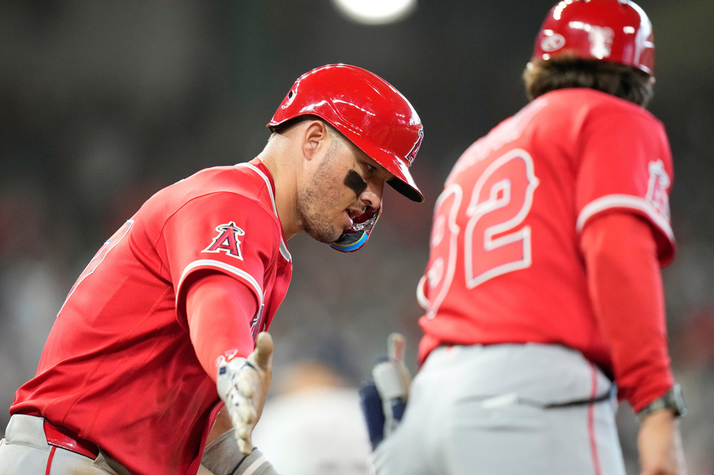 Los Angeles Angels' Mike Trout, left, celebrates with first base coach Adam Eaton (92) after hitting a home run against the Houston Astros during the seventh inning of an opening-day baseball game Thursday, March 26, 2026, in Houston. (AP Photo/David J. Phillip)