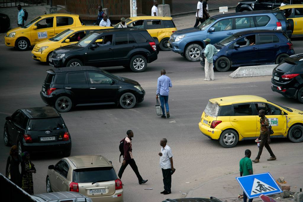 FILE - Pedestrians slalom between traffic to cross the road in Kinshasa, Congo, Tuesday Jan. 8, 2019. (AP Photo/Jerome Delay, file)