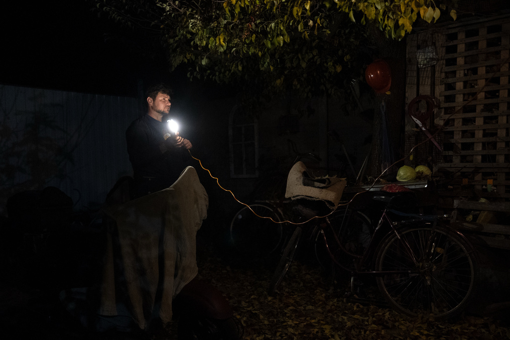 CORRECTS FAMILY NAME TO ADAMCHUK - Oleksandr Adamchuk rigs up a light in his yard to fix a moped, which the family will use to take the kids to school and run other errands, Friday, Oct. 24, 2025, in Kyiv region, Ukraine. (AP Photo/Julia Demaree Nikhinson)