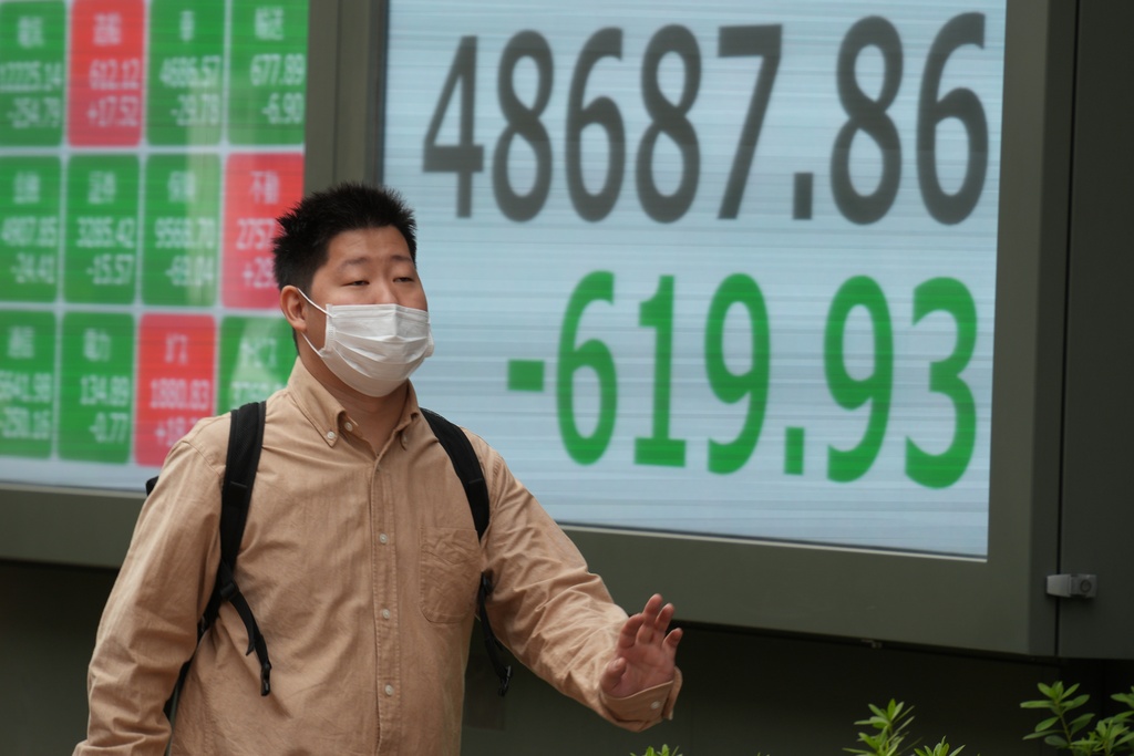 A person walks in front of an electronic stock board showing Japan's Nikkei index at a securities firm Thursday, Oct. 23, 2025, in Tokyo. (AP Photo/Eugene Hoshiko)