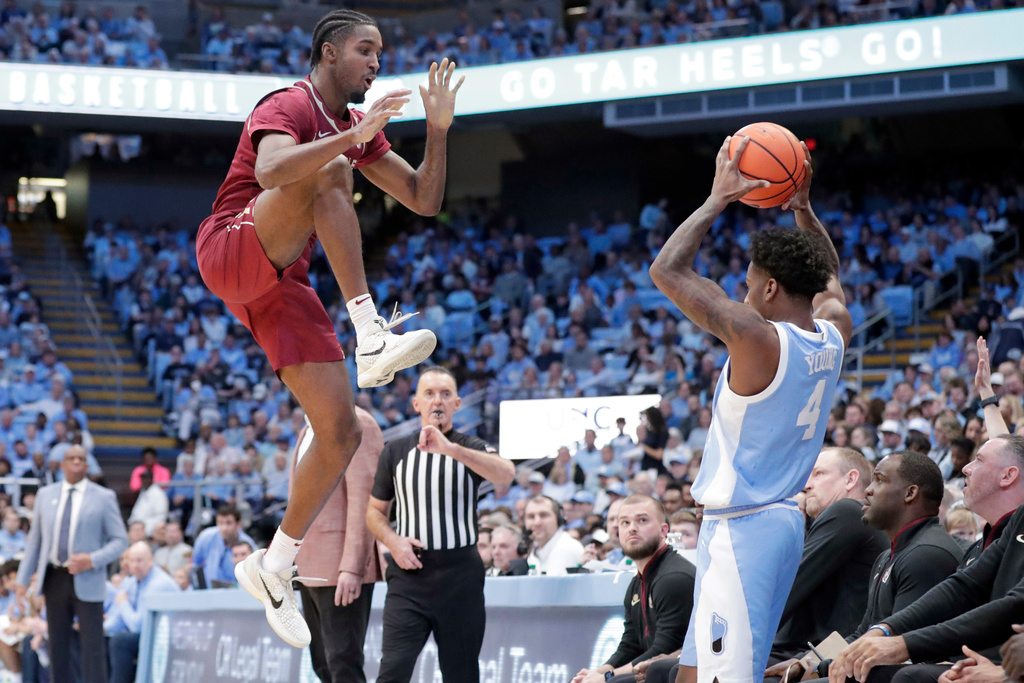 Florida State forward Chauncey Wiggins (7) goes high as he defends North Carolina guard Jaydon Young (4) during the frst half of an NCAA college basketball game Tuesday, Dec. 30, 2025, in Chapel Hill, N.C. (AP Photo/Chris Seward)