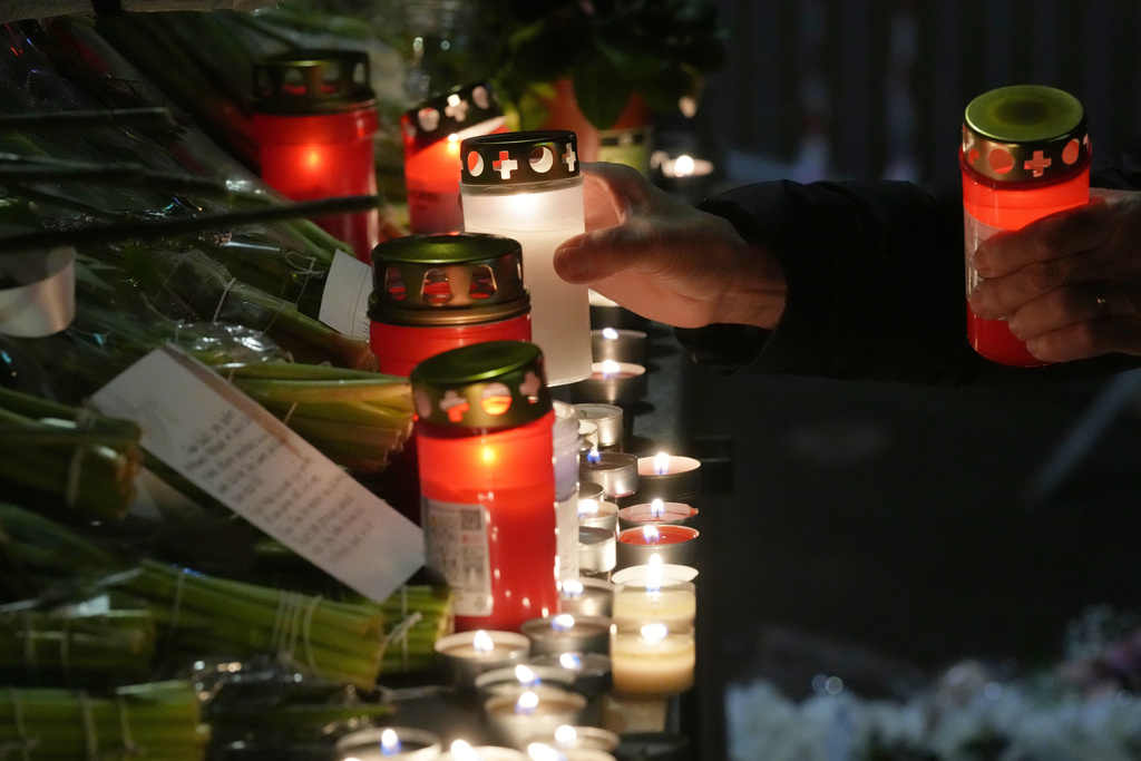 People lay candles and flowers near the Le Constellation bar, where a devastating fire left dead and injured during the New Year's celebrations in Crans-Montana, Swiss Alps, Switzerland, Thursday, Jan. 1, 2026. (AP Photo/ Antonio Calanni)