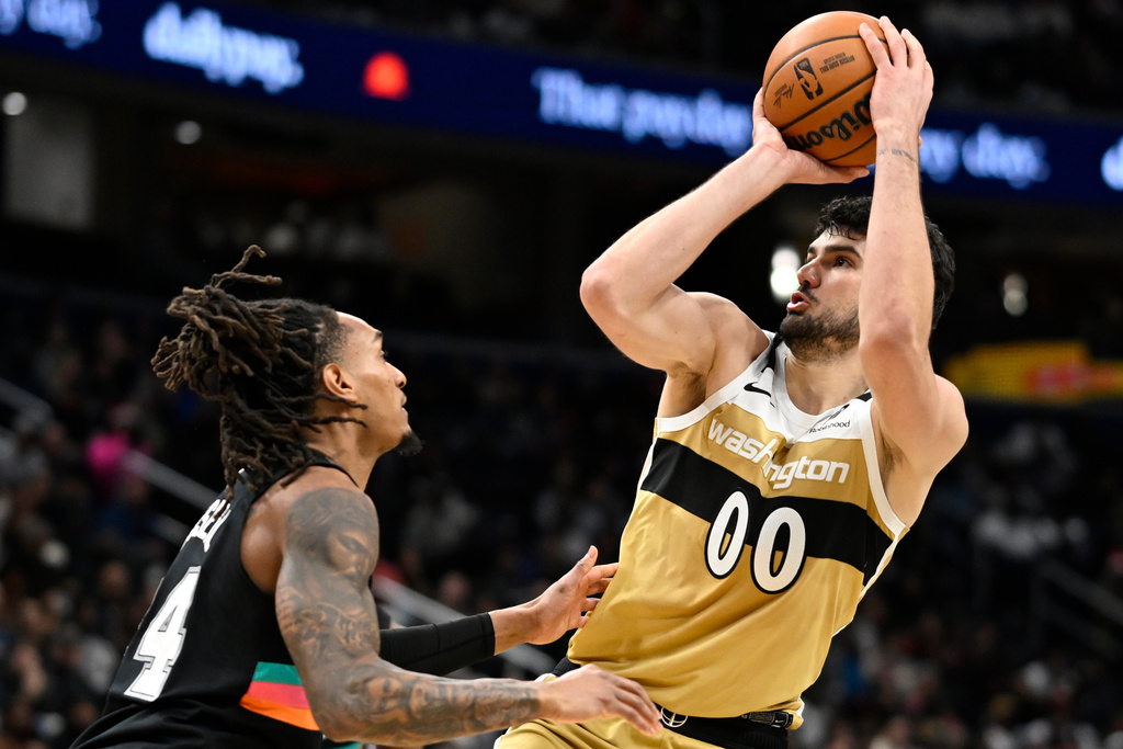 Washington Wizards forward Tristan Vukcevic (00) scores a basket over San Antonio Spurs guard Devin Vassell during the first half of an NBA basketball game, Sunday, Dec. 21, 2025, in Washington. (AP Photo/John McDonnell)