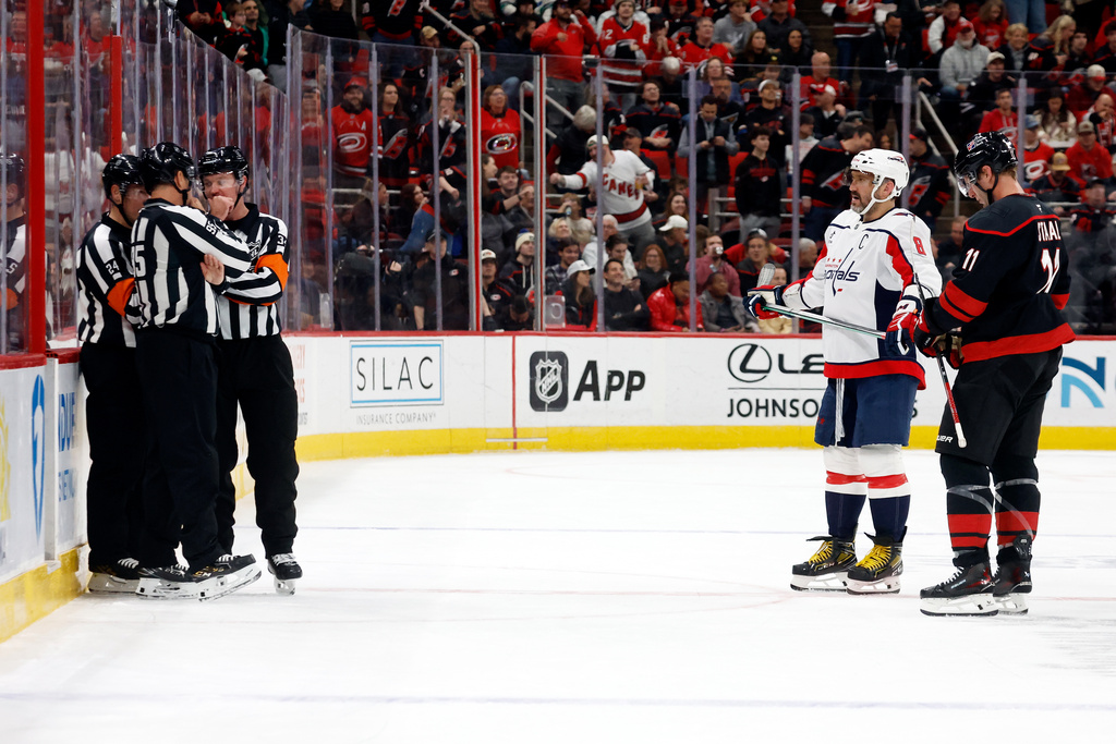 Officials gather as Carolina Hurricanes' Jordan Staal (11) and Washington Capitals' Alex Ovechkin (8) stand nearby during the first period of an NHL hockey game in Raleigh, N.C., Tuesday, Nov. 11, 2025. (AP Photo/Karl DeBlaker)