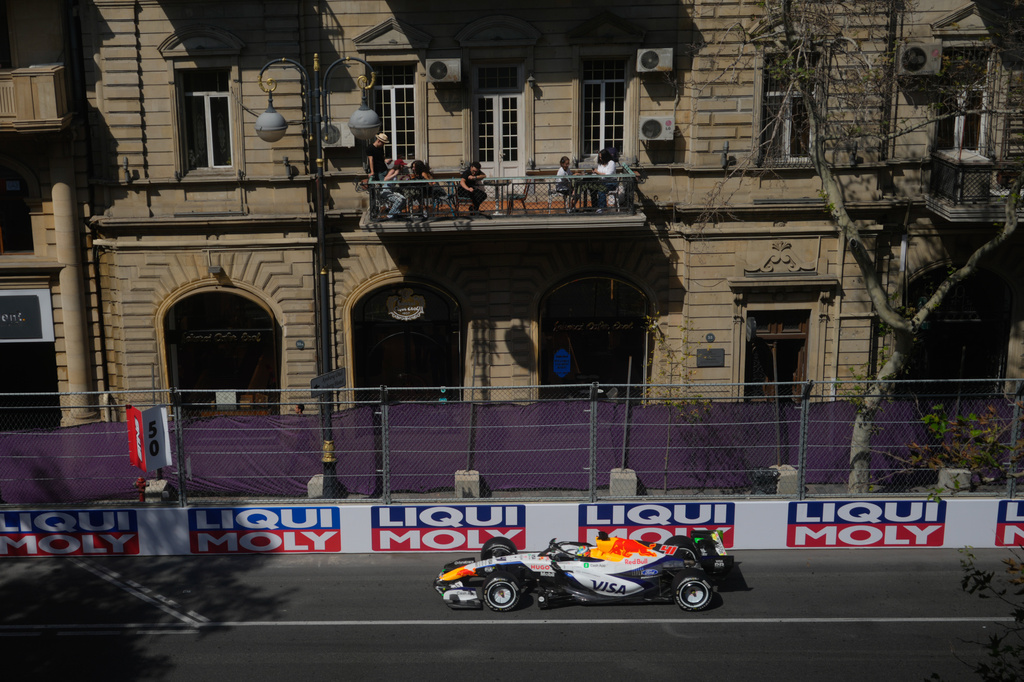 People watch from a balcony as Racing Bulls driver Arvid Lindblad of Britain steers his car during the first free practice ahead of the Azerbaijan F1 Grand Prix, in Baku, Azerbaijan, Thursday, Sept. 24, 2026. (AP Photo/Pavel Bednyakov)