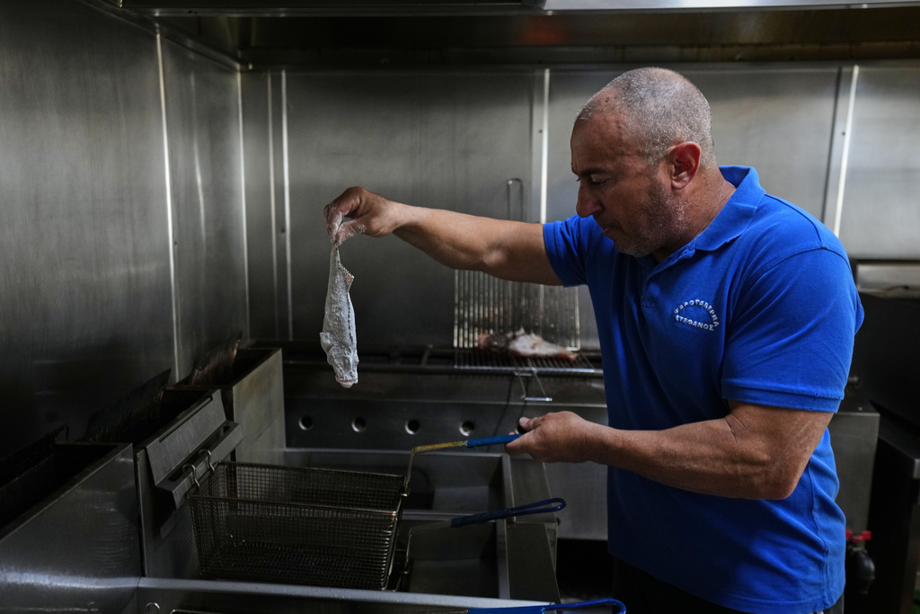 Stefanos Mentonis, owner of Stefanos restaurant, cooks lionfish in Larnaca, Cyprus, in the eastern Mediterranean, Thursday, Dec. 18, 2025. (AP Photo/Petros Karadjias)