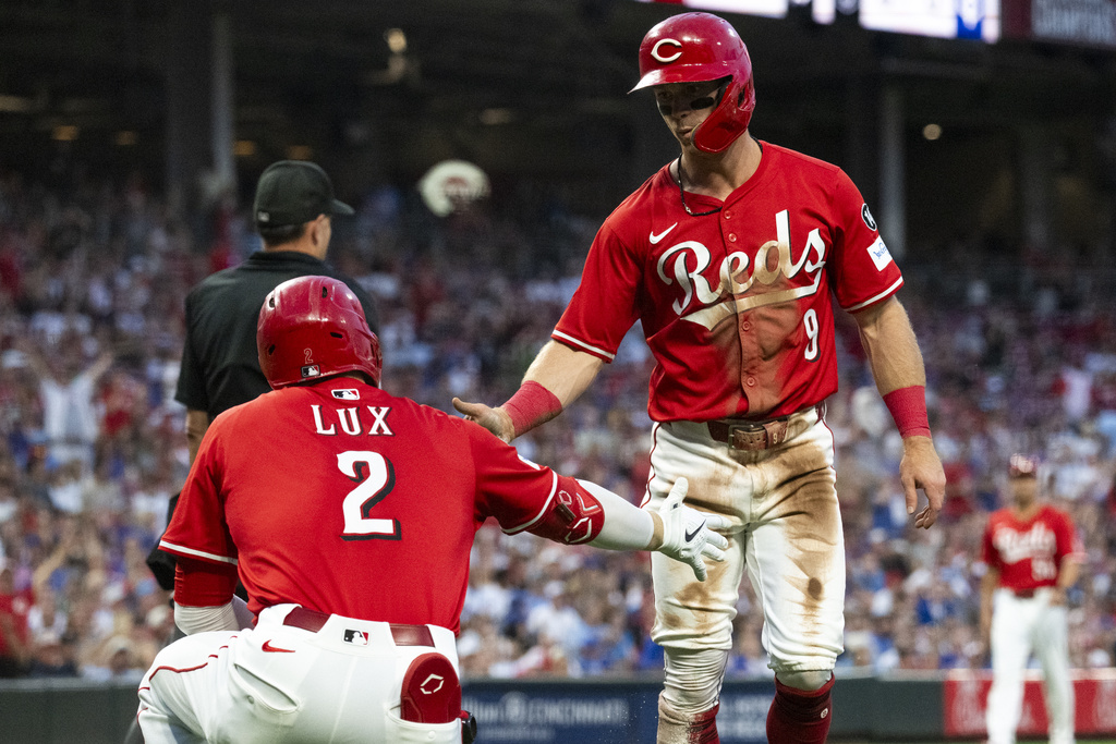 Cincinnati Reds' Matt McLain (9) and Gavin Lux (2) celebrate after McLain scored in the third inning of a baseball game against the Chicago Cubs, Saturday, Sept. 20, 2025, in Cincinnati. (AP Photo/Michael Swensen)