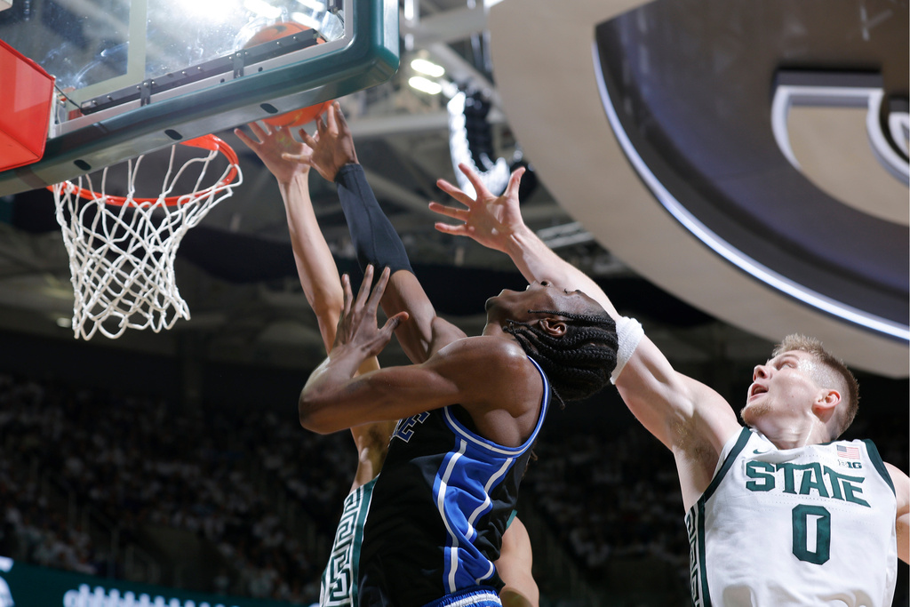 Duke guard Dame Sarr, center, and Michigan State forward Jaxon Kohler (0), right, and forward Jordan Scott, rear, vie for a rebound during the first half of an NCAA college basketball game, Saturday, Dec. 6, 2025, in East Lansing, Mich. (AP Photo/Al Goldis)