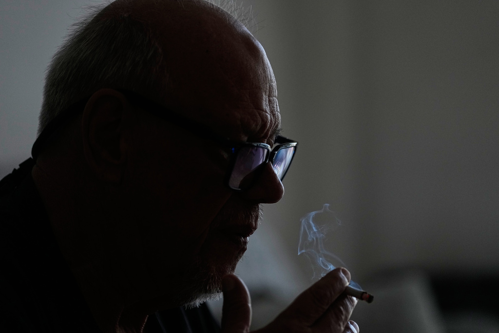 Former Army Lance Corporal and ex–Counter-Subversion Marksmen Unit Chief Juan Manuel Giraud lights a cigarette in his apartment in Buenos Aires, Argentina, Friday, March 13, 2026, as he serves a life sentence under house arrest after a 2022 conviction for the killing of members of a guerrilla group during a 1976 military operation. (AP Photo/Natacha Pisarenko)