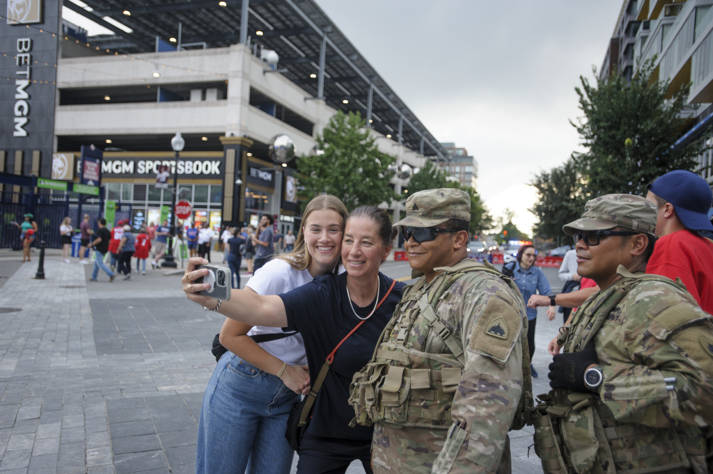 Women pose for a photo with members of the District of Columbia National Guard outside Nationals Park on game day in Washington, Wednesday, Aug. 20, 2025. (AP Photo/Rod Lamkey, Jr.)