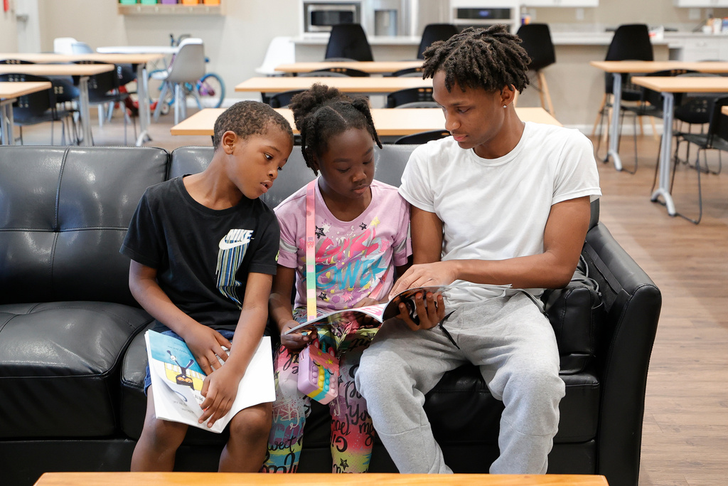 FILE - Karter Hardeman, 7, left, and Janayla Ralsey, 8, center, read with volunteer Joshua Banks, right, during an after-school literacy program through the Pure Hope Project in Atlanta on Thursday, April 6, 2023. (AP Photo/Alex Slitz, File) null
