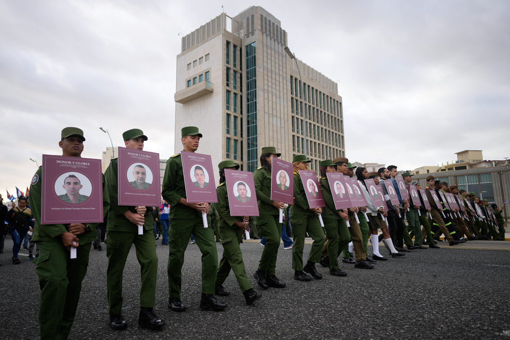 Soldiers carry photos of Cuban officers killed during the U.S. operation in Venezuela that captured Venezuelan President Nicolas Maduro, during a rally outside the U.S. Embassy in Havana, Cuba, Friday, Jan. 16, 2026. (AP Photo/Ramon Espinosa)
