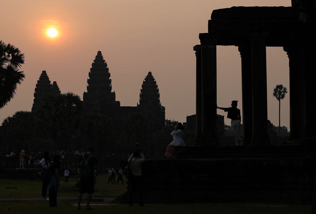 Visitors pose for photos as the sun rises over the ancient temple of Angkor Wat in Siem Reap, Cambodia on April 9, 2023. (AP Photo/Anton L. Delgado)
