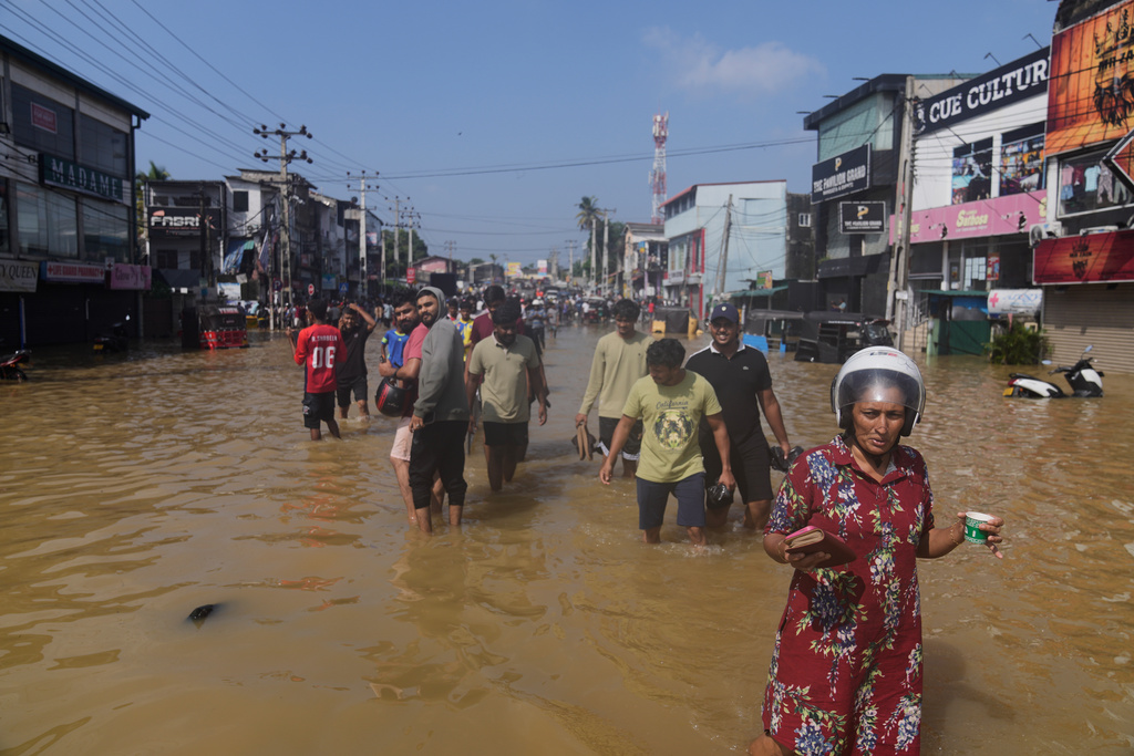 People wade through a submerged area of Colombo, Sri Lanka, following flooding on Sunday, Nov. 30, 2025. (AP Photo/Eranga Jayawardena)