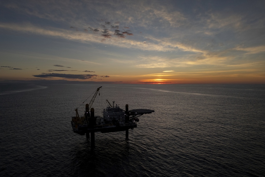 The sun sets behind the Liftboat Robert platform, home of Expedition 501, a global research expedition drilling for fresh water, in the North Atlantic, Saturday, July 19, 2025. (AP Photo/Carolyn Kaster)
