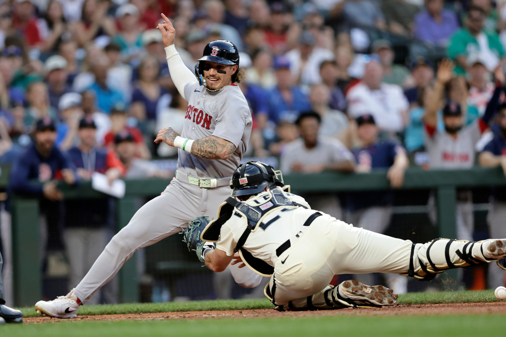 Boston Red Sox's Jarren Duran scores with Seattle Mariners catcher Cal Raleigh reaching with an empty glove during the seventh inning of a baseball game, Friday, June 19, 2026, in Seattle. (AP Photo/John Froschauer)