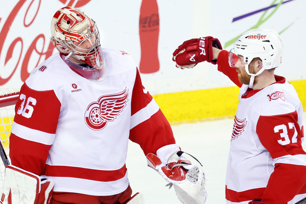 Detroit Red Wings goalie John Gibson, left, is congratulated by J.T. Compher after defeating the Calgary Flames in NHL hockey action in Calgary, on Wednesday, Dec. 10, 2025. (Larry MacDougal/The Canadian Press via AP)