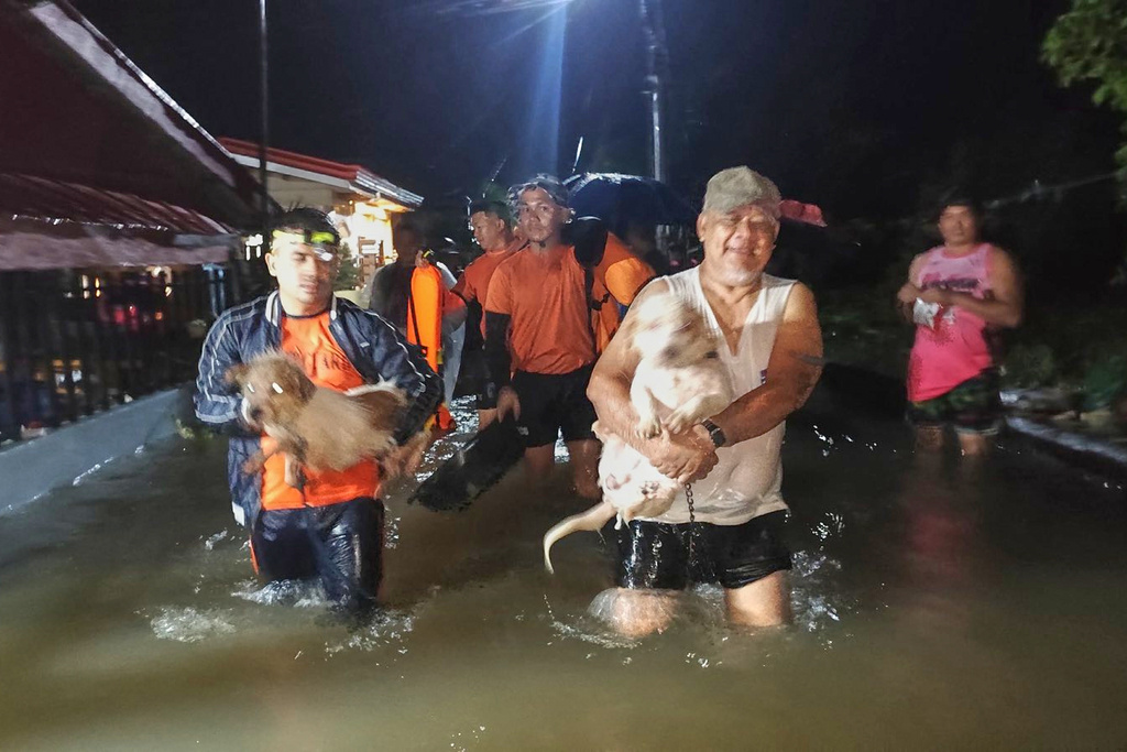In this handout provided by the Philippine Coast Guard, residents and their dogs are evacuated by rescuers as floods rise due to Typhoon Bualoi in Ormoc, Leyte province, Philippines, on Friday Sept. 26, 2025. (Philippine Coast Guard via AP)