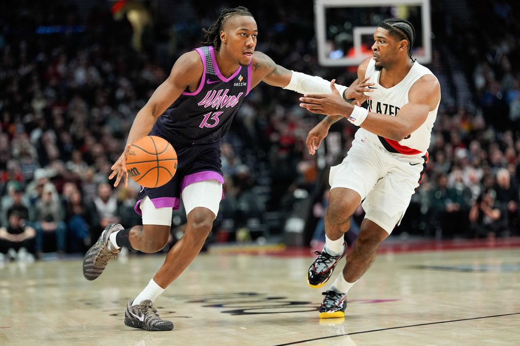Minnesota Timberwolves guard Ayo Dosunmu (13) drives to the basket past Portland Trail Blazers guard Scoot Henderson during the second half of an NBA basketball game Tuesday, Feb. 24, 2026, in Portland, Ore. (AP Photo/Jenny Kane)