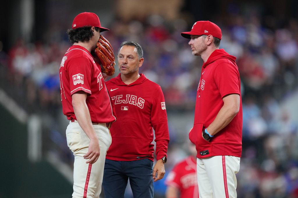 Texas Rangers starting pitcher Cal Quantrill, left, talks to head athletic trainer Matt Lucero, center, and pitching coach Jordan Tiegs during the second inning of a baseball game against the Toronto Blue Jays, Saturday, Sept. 19, 2026, in Arlington, Texas. (AP Photo/Julio Cortez)