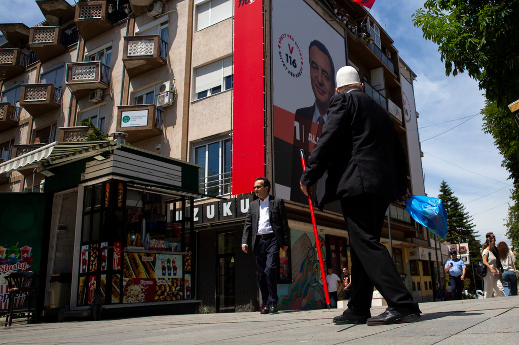 People pass by a giant election poster of acting prime minister Albin Kurti, in capital Pristina, Kosovo, Friday, June 5, 2026, ahead of snap parliamentary elections on June 7. (AP Photo/Visar Kryeziu)