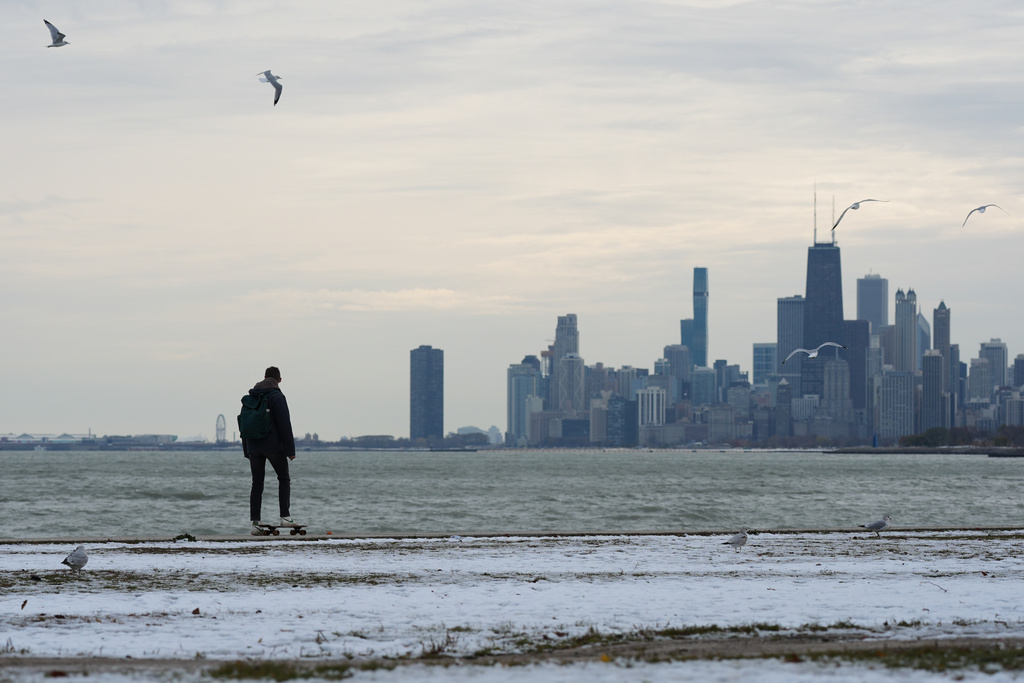 A man bundles up as he skateboards in the snow-covered at Lake Michigan during a cold day in Chicago, Tuesday, Nov. 11, 2025. (AP Photo/Nam Y. Huh)