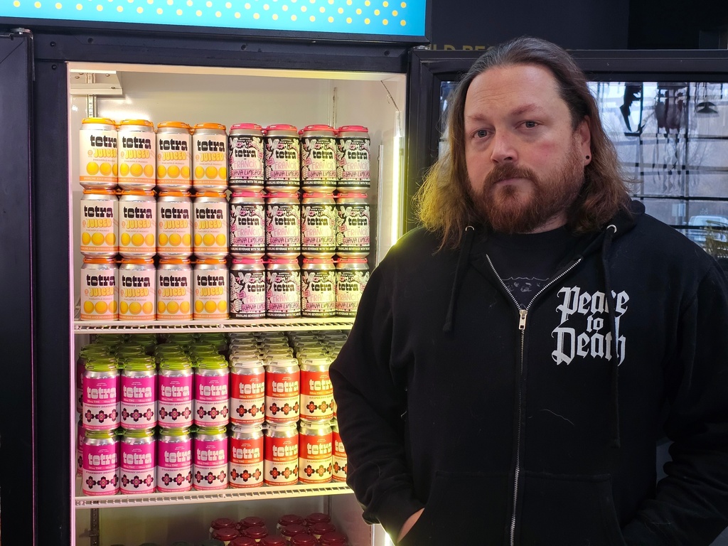 Drew Hurst, president and chief operating officer of Bauhaus Brew Labs in Minneapolis, stands outside a cooler for cans of seltzer containing THC, the active ingredient in marijuana, in his brewery's taproom on Thursday, Nov. 20, 2025. (AP Photo/Steve Karnowski)