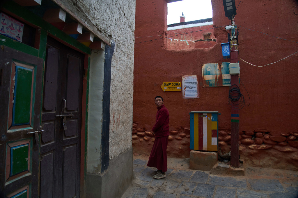 A Buddhist monk walks in an alley as a CCTV camera mounted on a pole watches over the area in the ancient ethnic Tibetan city of Mustang, Nepal, April 18, 2025. (AP Photo/Niranjan Shrestha)