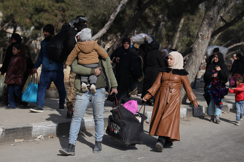 Residents carry their belongings as they are fleeing from Sheikh Maqsoud and Achrafieh neighborhoods after clashes broke out on Tuesday between Syrian government forces and Kurdish fighters in a contested area of the northern city of Aleppo, Syria, Wednesday, Jan. 7, 2026. (AP Photo/Omar Albam)
