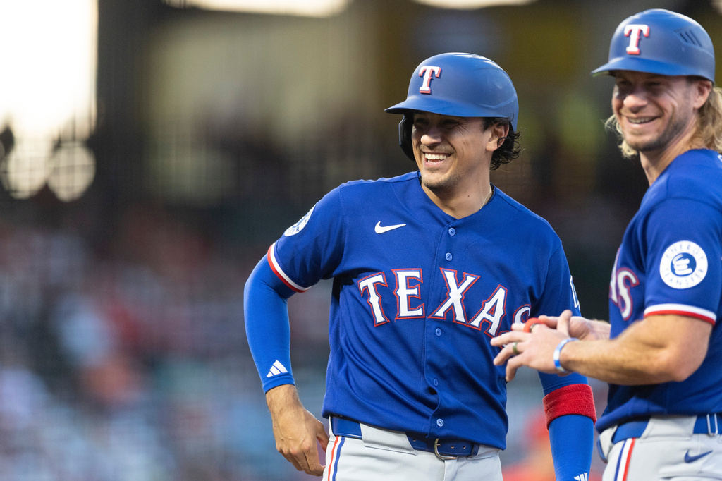 Texas Rangers' Nicky Lopez smiles with Texas Rangers first base coach Travis Jankowski after being hit by a pitch in the second inning of a baseball game against the Los Angeles Angels Wednesday, Aug. 12, 2026, in Anaheim, Calif. (AP Photo/Karl Anderson)