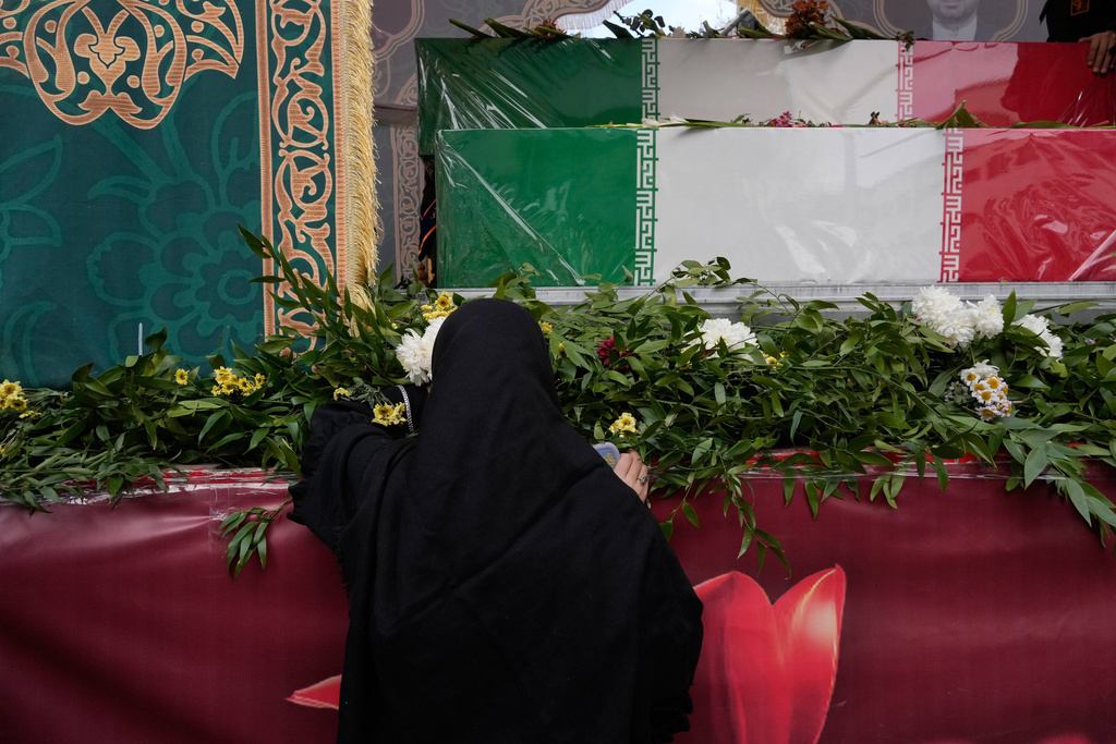 A woman mourns next to the flag-draped coffins of a group of security forces, who were killed during anti-government protests, during their funeral ceremony, in Tehran, Iran, Wednesday, Jan. 14, 2026. (AP Photo/Vahid Salemi)
