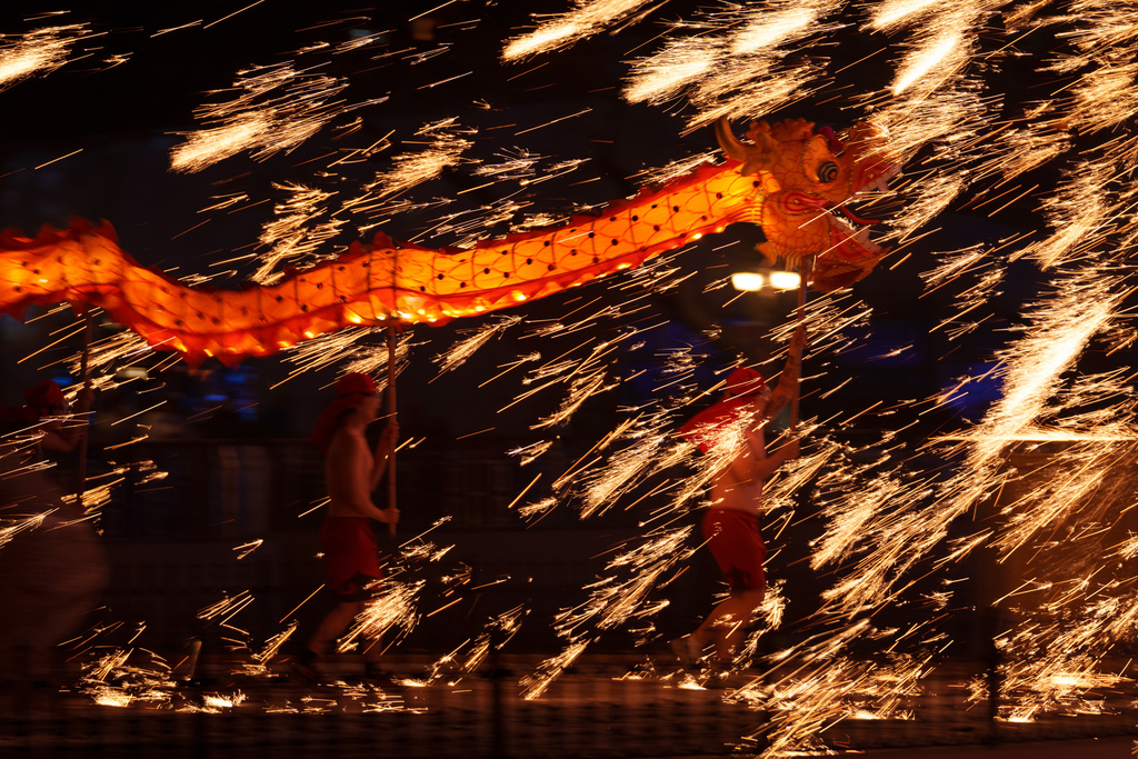 Fire performers carry a dragon during a molten iron fireworks performance known as "fire dragon steel flowers" ahead of Lunar New Year celebrations at an amusement park on the outskirts of Beijing, China, Saturday, Feb. 14, 2026. (AP Photo/Vincent Thian)
