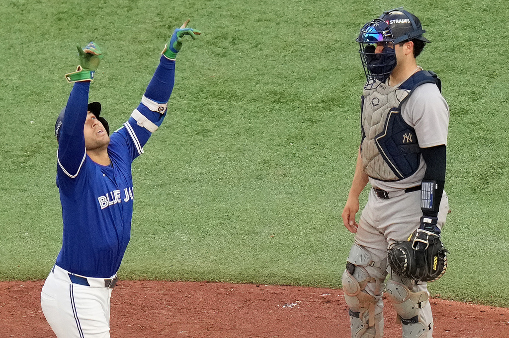 Toronto Blue Jays designated hitter George Springer, left, celebrates after hitting a solo home run as New York Yankees catcher Austin Wells, right, looks on during the fifth inning of Game 2 of baseball's American League Division Series in Toronto, Sunday, Oct. 5, 2025. (Chris Young/The Canadian Press via AP)
