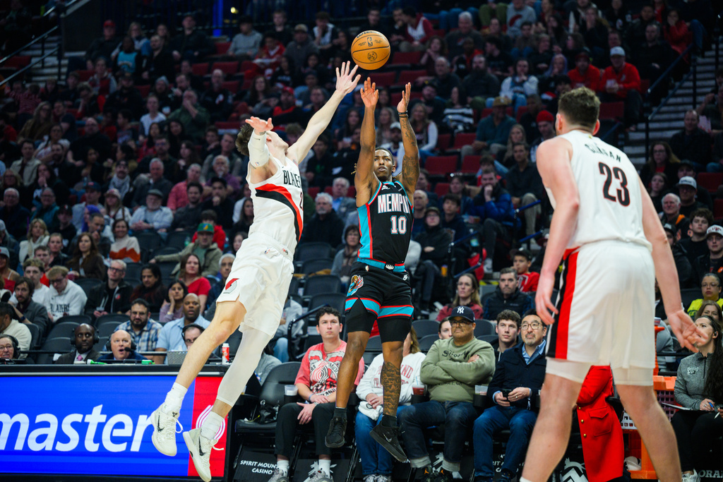 Memphis Grizzlies guard Javon Small, center, shoots a 3-point basket past Portland Trail Blazers guard Vit Krejci, left, during the first half of an NBA basketball game Friday, Feb. 6, 2026, in Portland, Ore. (AP Photo/Molly J. Smith)
