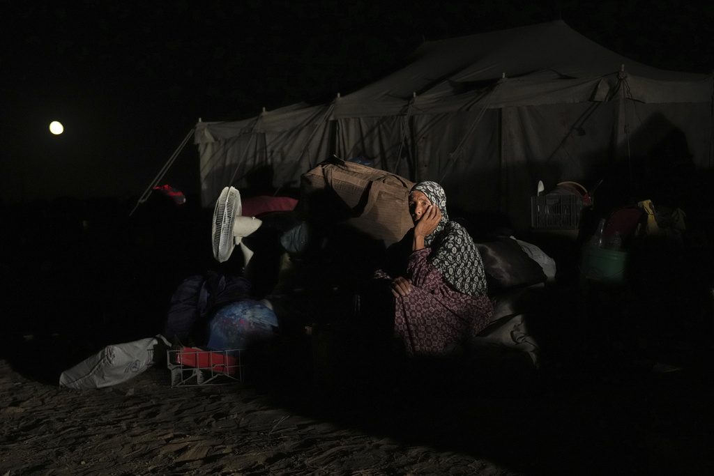Awatif Abu Jarad, 57, sits beside her family's belongings in Khan Younis, Gaza Strip, Sept. 10, 2025, after fleeing Gaza City following evacuation orders issued by the Israeli army. (AP Photo/Abdel Kareem Hana)