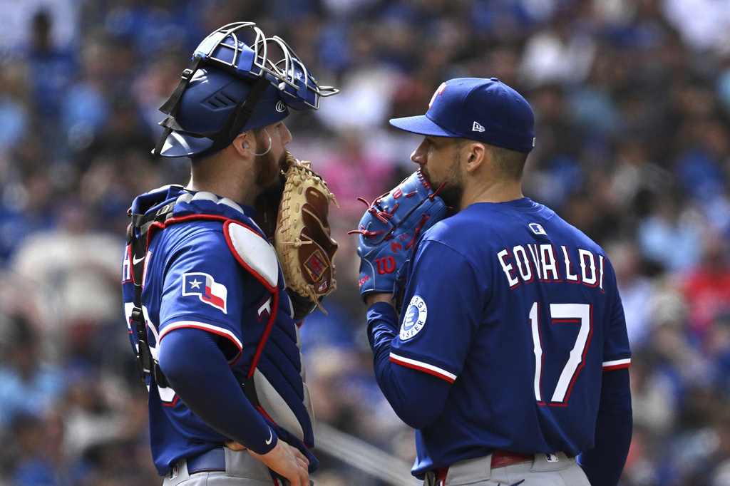 Texas Rangers catcher Jonah Heim, left, visits Texas Rangers starting pitcher Nathan Eovaldi (17) on the mound during sixth-inning baseball action in Toronto, on Sunday, Aug. 17, 2025. (Jon Blacker/The Canadian Press via AP)