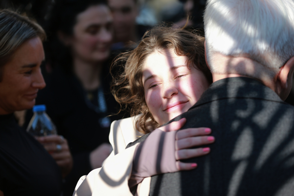 Bella May Culley, center, 19-year-old, who was arrested upon arrival at the Tbilisi Airport in May and accused of attempting to smuggle marijuana and hashish into the country, embraces her lawyer Malkhaz Salakaia, back to a camera, after she was released from prison near the court building in Tbilisi, Georgia, on Monday, Nov. 3, 2025. (AP Photo/Zurab Tsertsvadze)