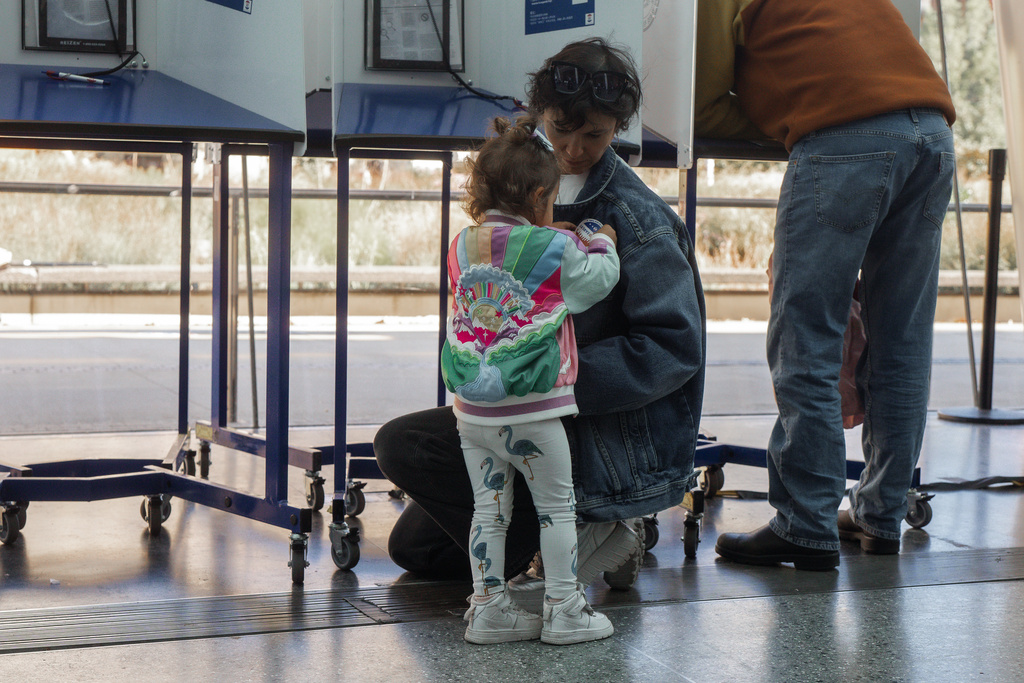 A child places a sticker on a jacket during early voting on Saturday, Oct. 25, 2025, in New York. (AP Photo/Olga Fedorova)