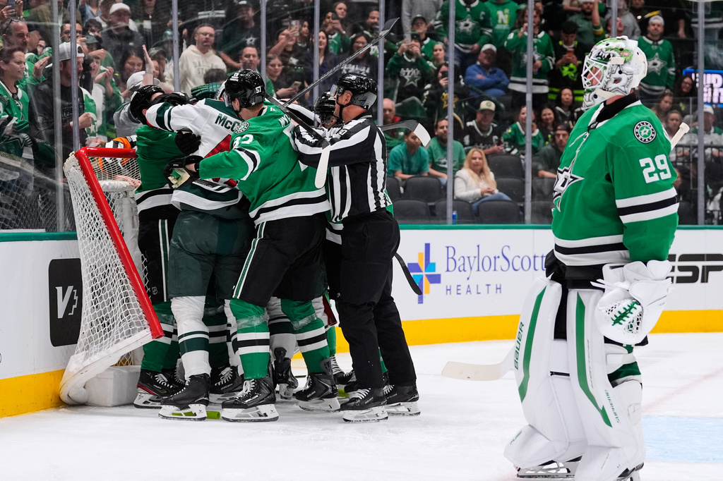 Dallas Stars goaltender Jake Oettinger, right, skates away as teammates and Minnesota Wild players fight in the second period of an NHL hockey game Thursday, April 9, 2026, in Arlington, Texas. (AP Photo/Tony Gutierrez)