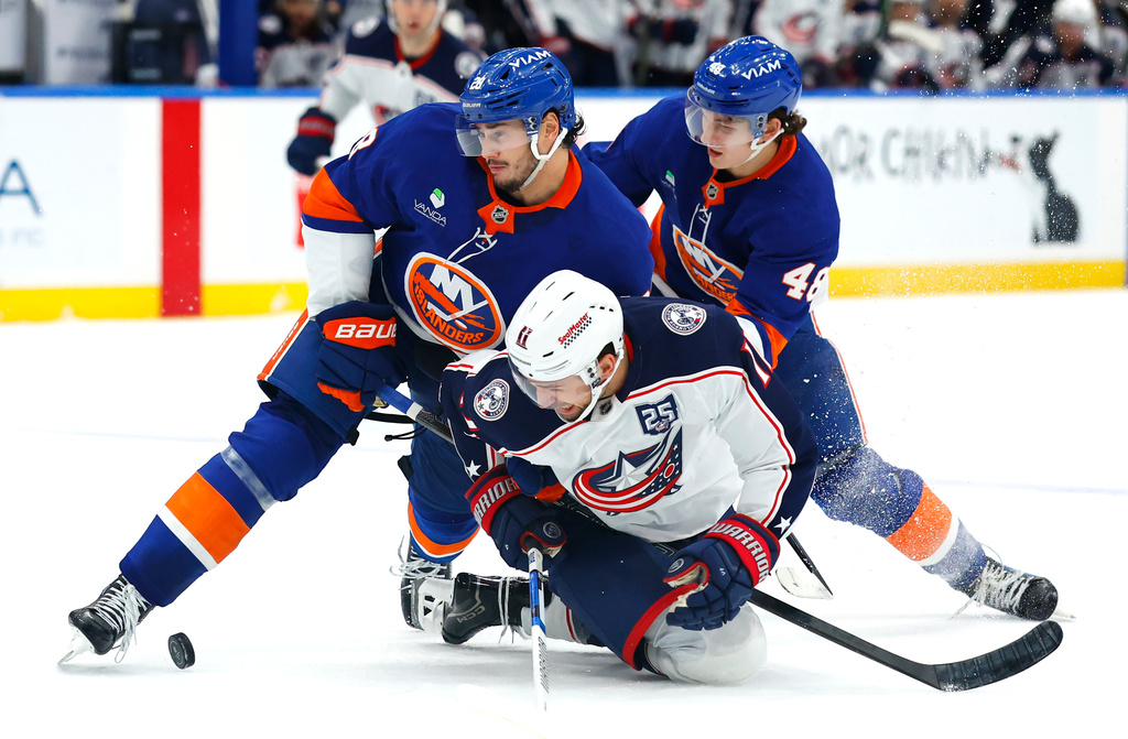 New York Islanders defensemen Alexander Romanov (28) and Matthew Schaefer (48) battle Columbus Blue Jackets left wing Miles Wood (11) for the puck during the third period of an NHL hockey game, Sunday, Nov. 2, 2025, in New York. (AP Photo/Noah K. Murray)