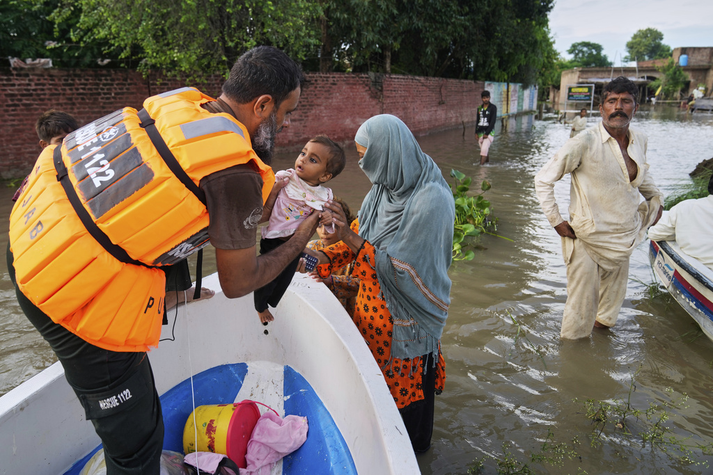 A rescue worker helps a family board in a boat to evacuate them from a flooded area in Dhoop Sarhi village in Kasur district, Pakistan, Tuesday, Aug. 26, 2025, due to the rising water level in Sutlej River, following neighboring India releasing water from overflowing dams. (AP Photo/K.M. Chaudary)