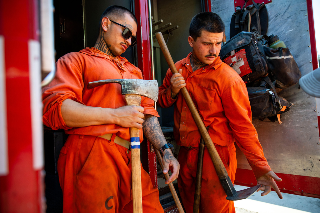Damien Rubalcava, left, unloads tools after work at the Pine Grove Youth Conservation Camp, July 14, 2025, in Red Corral, Calif. (AP Photo/Ethan Swope)