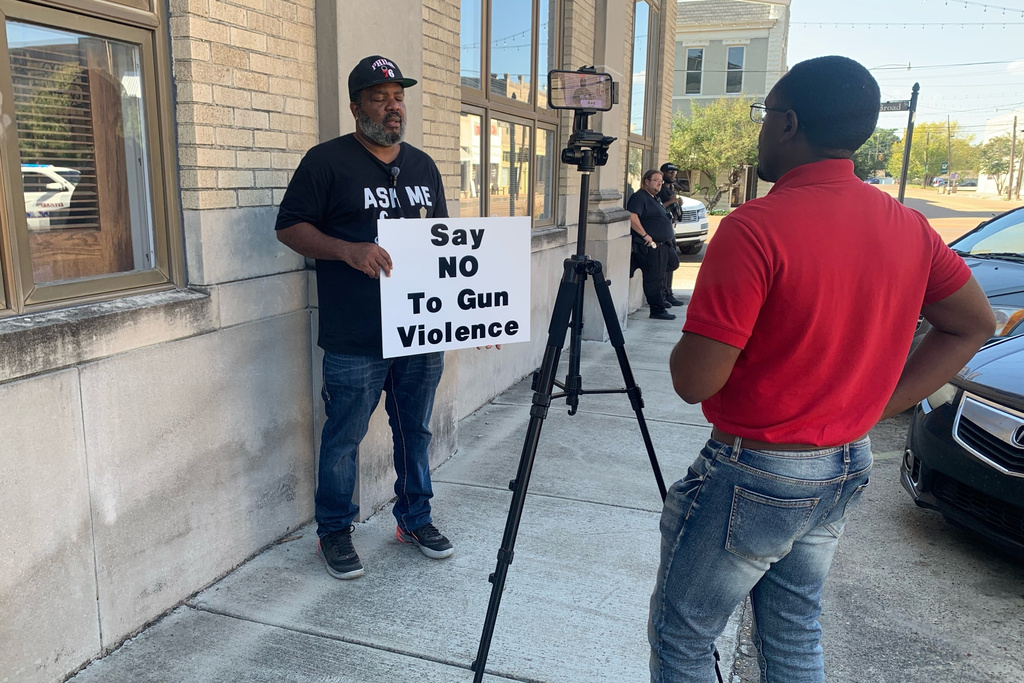A man holds a sign as he is interviewed after a deadly shooting Friday night in downtown Leland, Miss.,on Saturday, Oct. 11, 2025. (AP Photo/Katie Adkins)