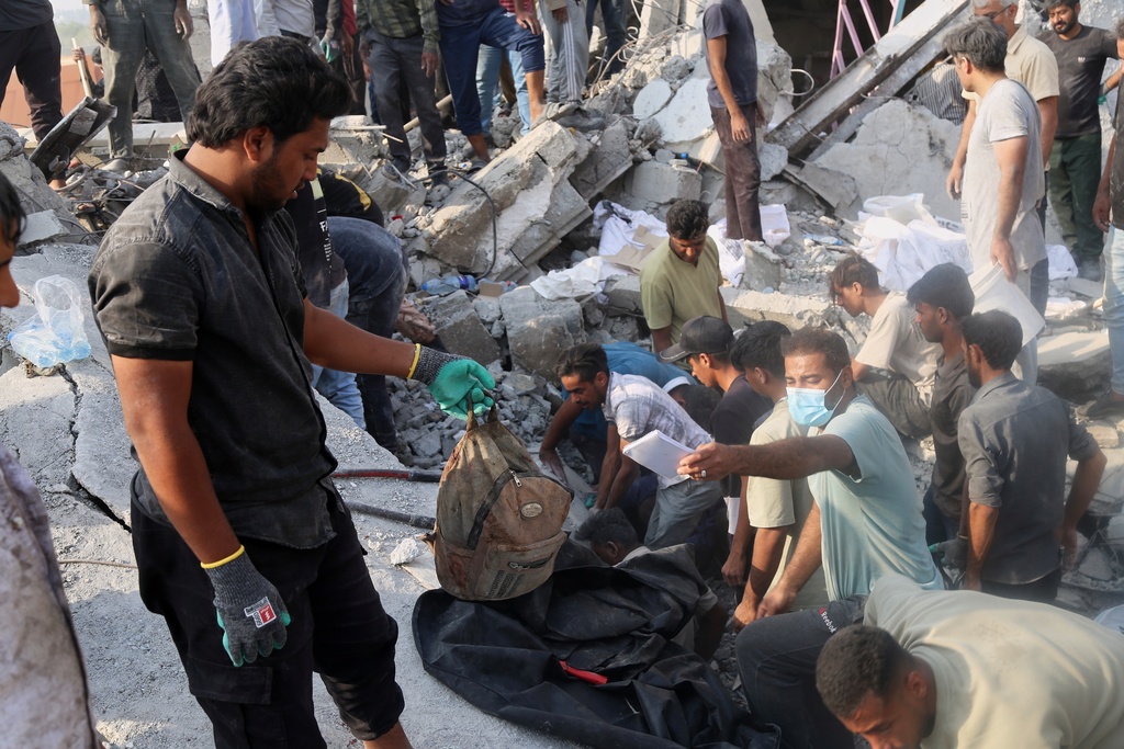 A man hold a children's backpack as rescue workers and residents search through the rubble in the aftermath of a strike on a girls' elementary school in Minab, Iran, Saturday, Feb. 28, 2026. (Abbas Zakeri/Mehr News Agency via AP)