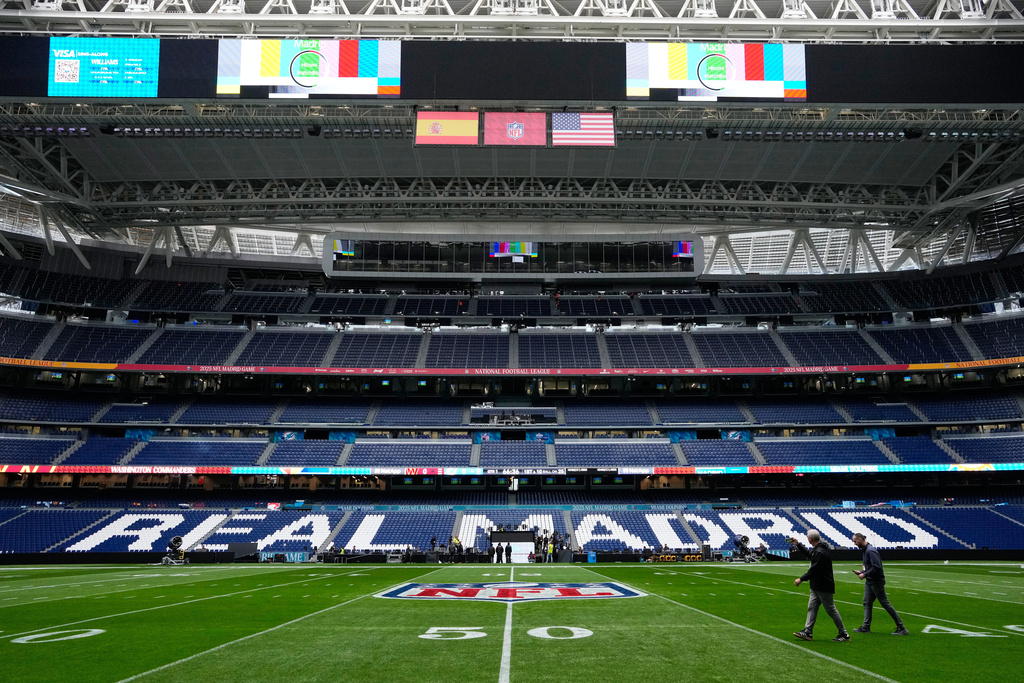 Workers prepare the field at the Santiago Bernabeu stadium ahead of an NFL game between the Miami Dolphins and Washington Commanders in Madrid, Spain, Friday, Nov. 14, 2025. (AP Photo/Steve Luciano)