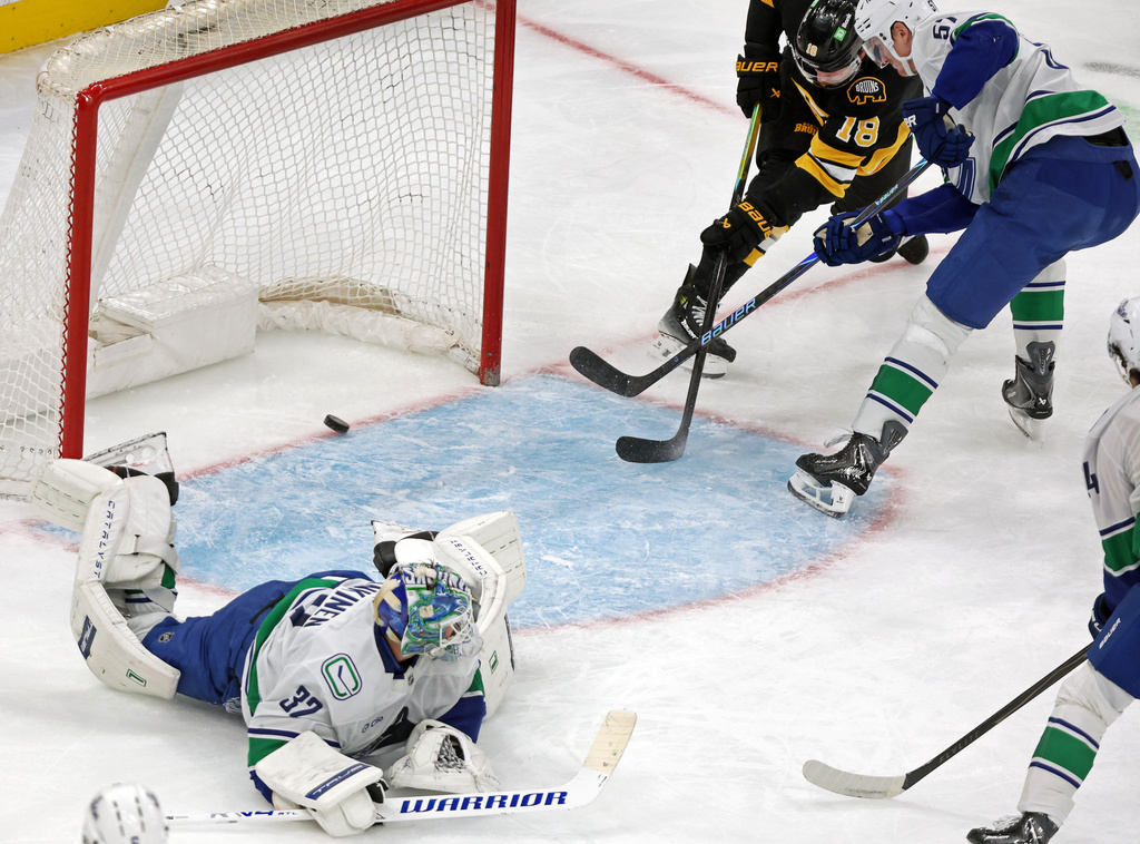 Boston Bruins forward Paval Zacha (18) puts the puck into the uncovered net as Vancouver Canucks goalie Kevin Lankinen is sprawled on the ice for a second period goal during an NHL hockey game, Saturday, Dec. 20, 2025, in Boston. (AP Photo/Jim Davis)