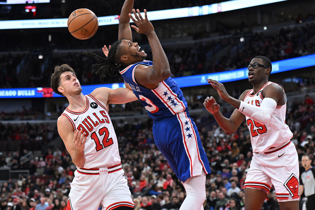 Philadelphia 76ers' Jabari Walker, center, battles Chicago Bulls' Zach Collins (12) and Jalen Smith, right, for a rebound during the first half of an NBA basketball game, Friday, Dec. 26, 2025, in Chicago. (AP Photo/Paul Beaty)