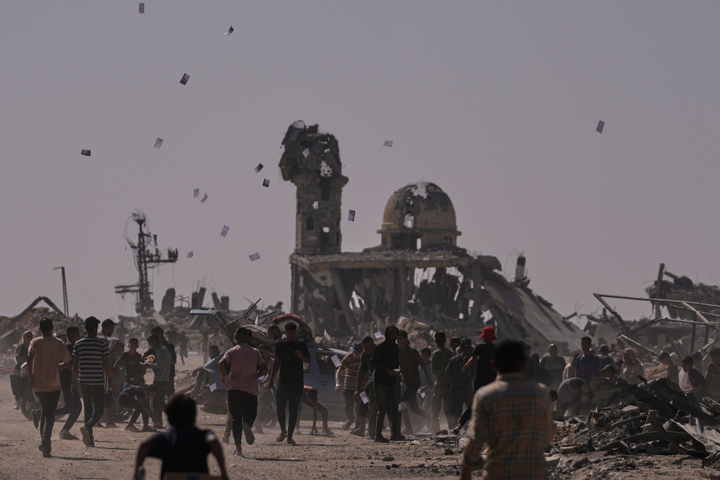 Palestinians collect leaflets dropped by an Israeli drone warning people to stay away from the so-called yellow line in Khan Younis, in the southern Gaza Strip, Monday, Oct. 20, 2025. (AP Photo/Jehad Alshrafi)