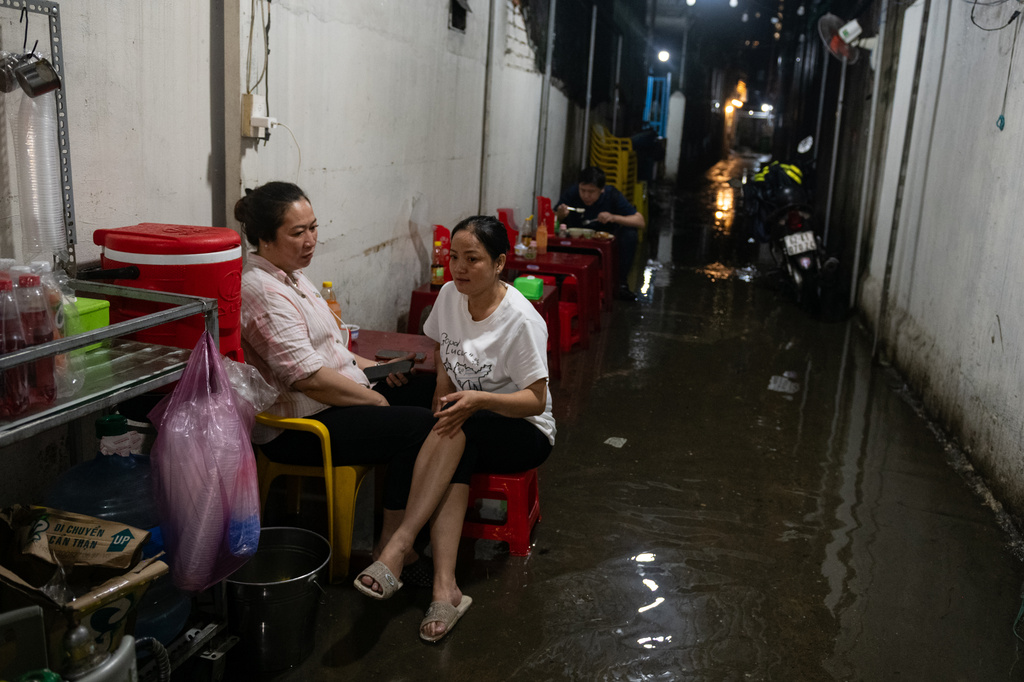 People sit by a flooded alleyway eatery on Pham Huu Lau Street in Ho Chi Minh City, Vietnam, Wednesday, Sept. 30, 2026. (AP Photo/Thanh Hue)